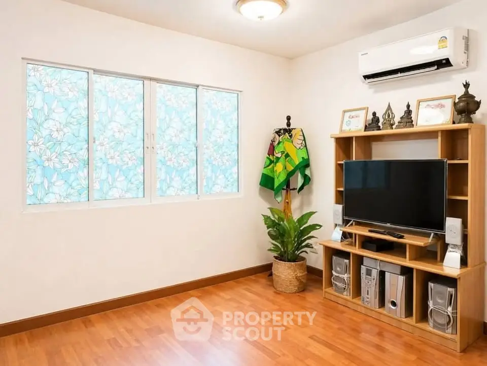 Cozy living room with wooden flooring, air conditioning, and entertainment center.