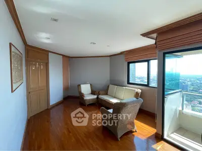 Spacious living room with wooden flooring and panoramic city view from large windows.