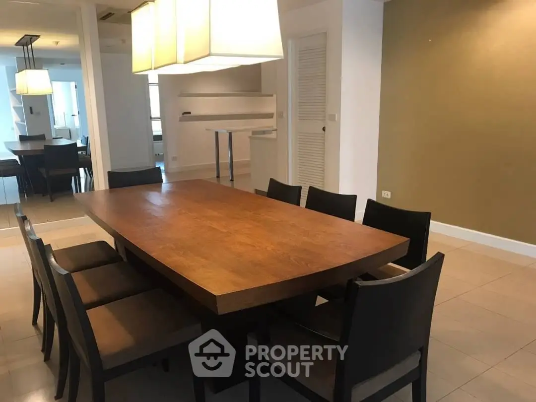 Spacious dining area with elegant wooden table and modern lighting in a stylish home.