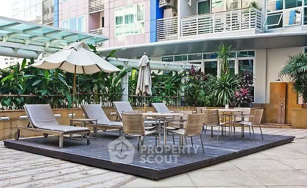 Luxurious outdoor patio with modern furniture and lush greenery in a high-end residential complex.