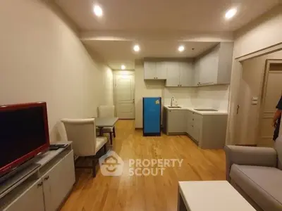 Cozy living room with modern kitchen, wooden flooring, and stylish furniture in a compact apartment.