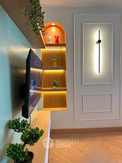 Modern living room with stylish wall decor and mounted TV, featuring elegant lighting and wooden flooring.