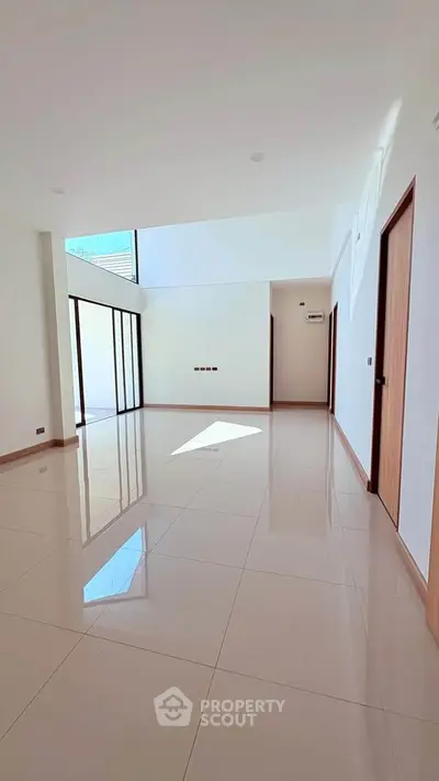 Spacious modern living room with large windows and glossy tiled floors