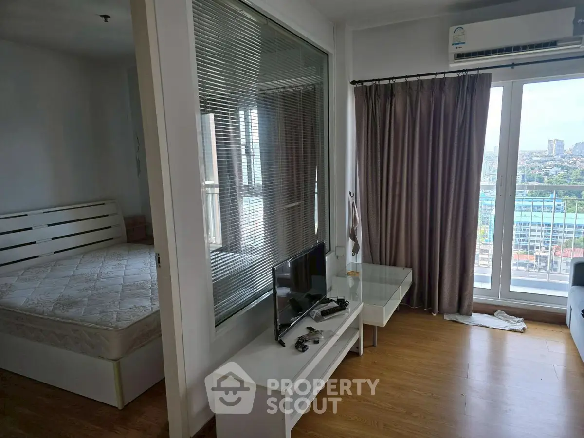 Modern apartment with bedroom and living area, featuring large windows and a city view.