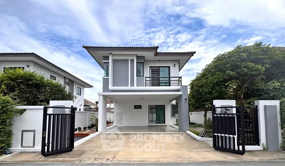 Modern two-story house with gated driveway and lush greenery, perfect for family living.