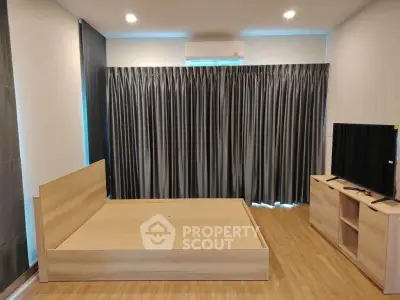 Modern bedroom with wooden flooring, bed frame, and TV unit, featuring sleek curtains and air conditioning.