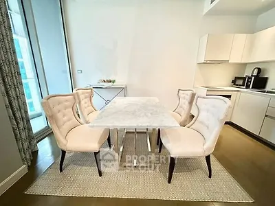 Elegant dining area with marble table and plush chairs in modern kitchen setting.
