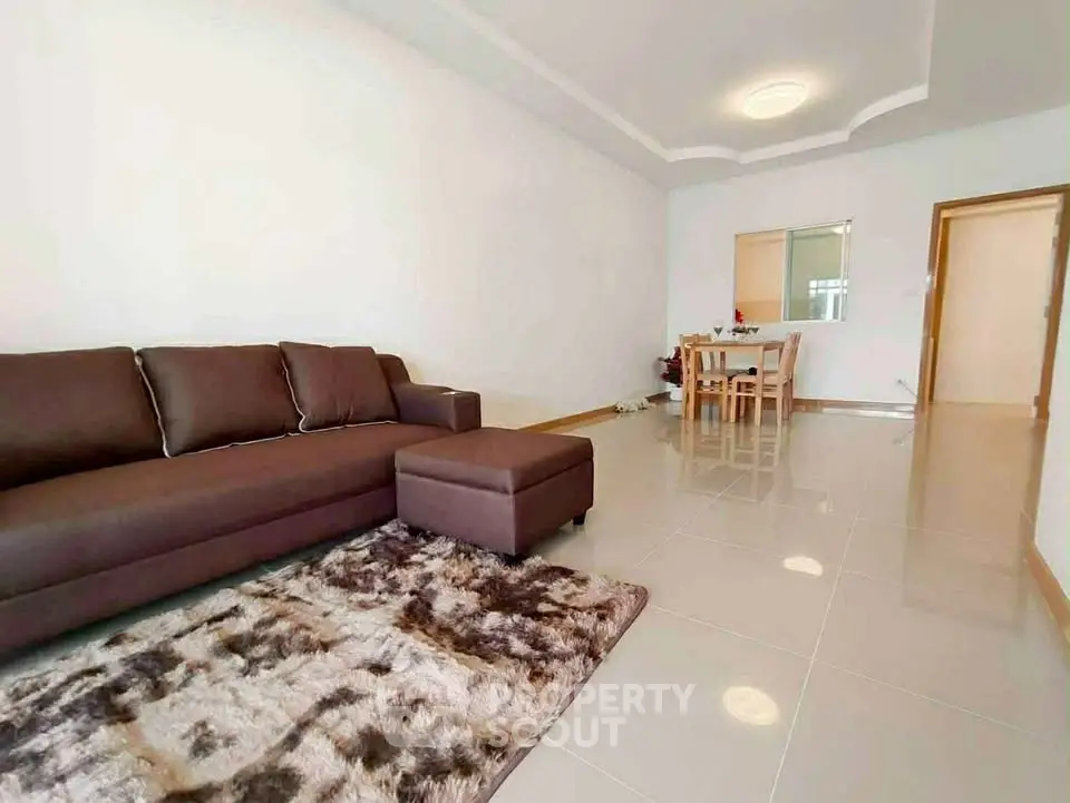 Spacious living room with modern brown sofa and elegant dining area.