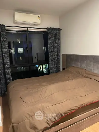 Cozy bedroom with modern decor and large window offering natural light.
