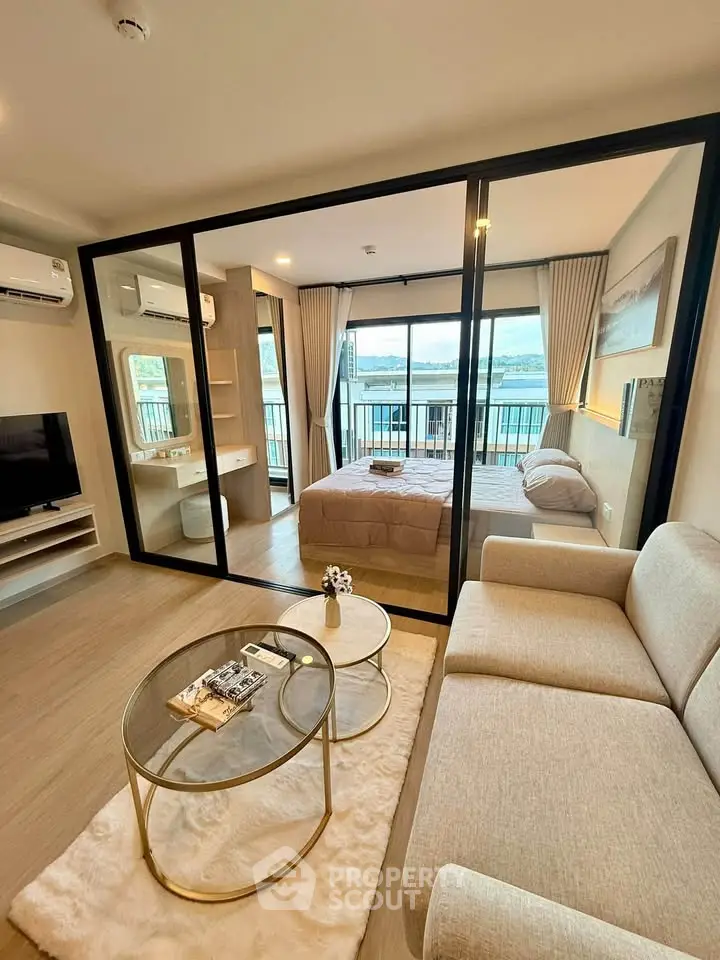 Modern studio apartment with glass partition, cozy living area, and stunning balcony view.