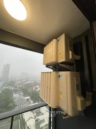 High-rise balcony with air conditioning units and city view on a foggy day.