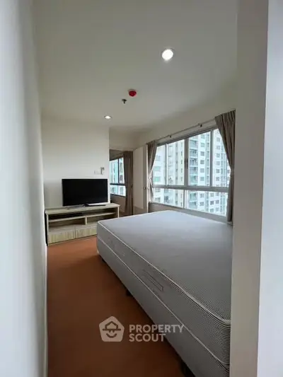 Spacious bedroom with large windows and natural light in modern apartment.