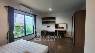 Spacious bedroom with large window and modern furnishings in a stylish home.