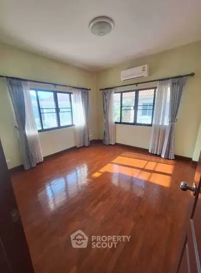 Spacious bedroom with hardwood floors and large windows for natural light.