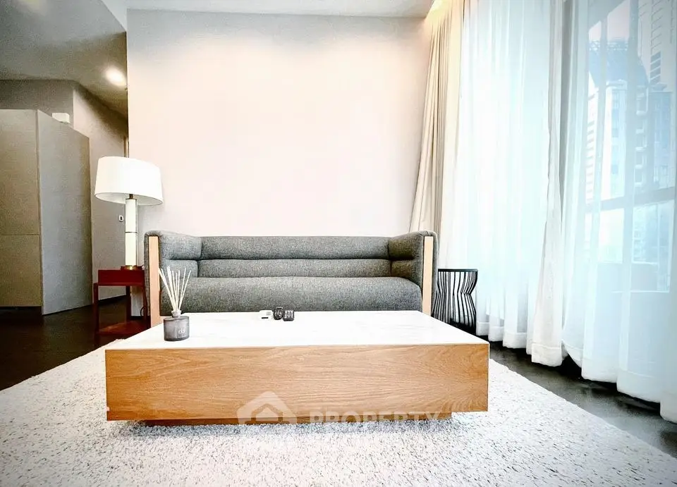 Modern living room with stylish sofa and coffee table, featuring floor-to-ceiling windows for natural light.