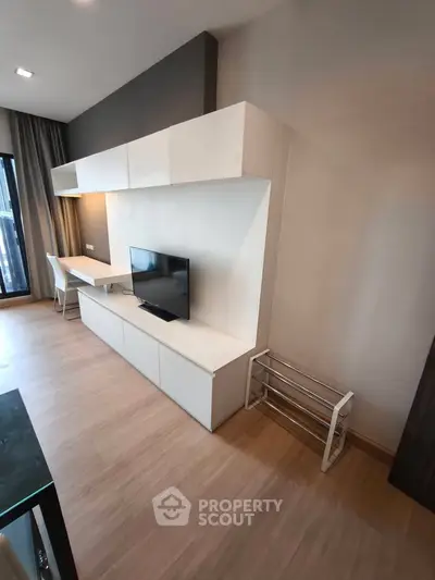 Modern living room with sleek TV unit and workspace, featuring stylish wood flooring and natural light.