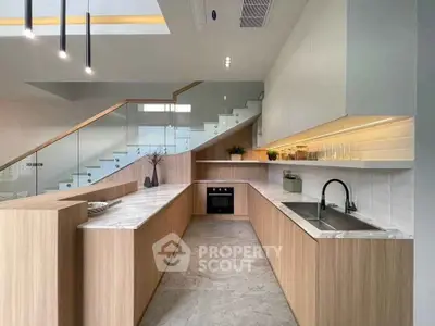 Modern kitchen with sleek design and open layout, featuring marble countertops and wooden cabinetry.