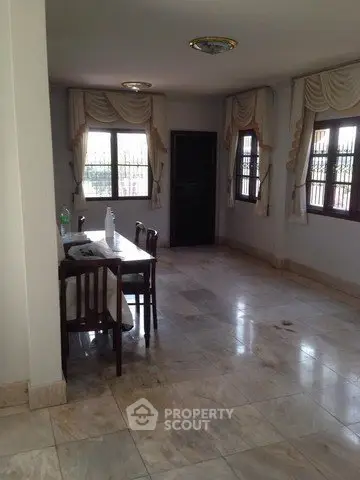 Spacious dining area with marble flooring and elegant window drapes in a well-lit room.