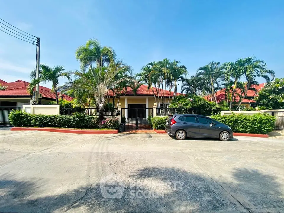 Charming suburban house with lush palm trees and red-tiled roof, perfect for family living.