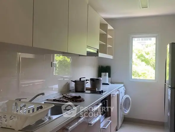 Modern kitchen with sleek cabinets, washing machine, and bright window view.
