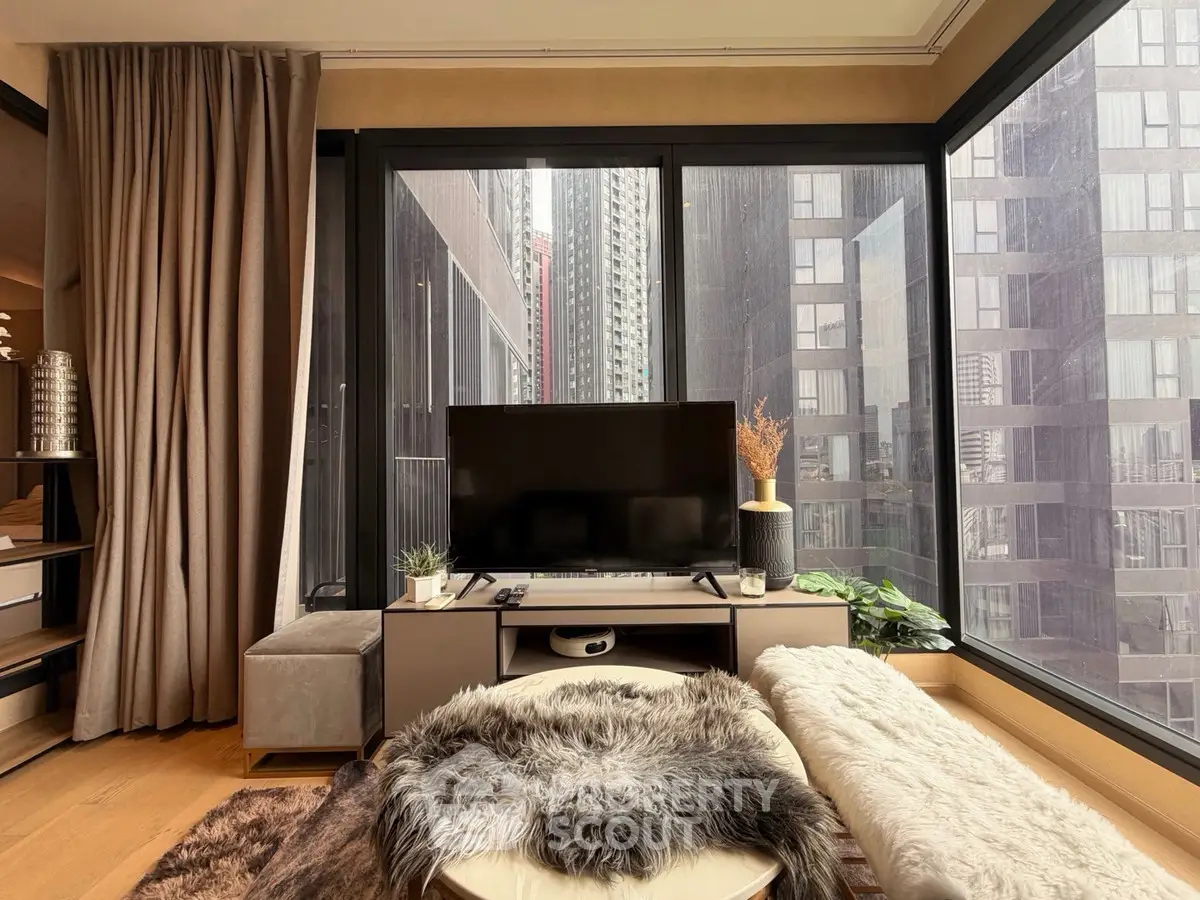 Modern living room with large windows and city view, featuring stylish decor and cozy seating area.