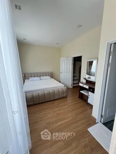 Spacious bedroom with elegant wooden flooring and modern furnishings