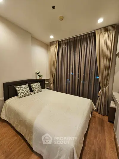 Cozy bedroom with elegant curtains and wooden flooring, perfect for relaxation and comfort.