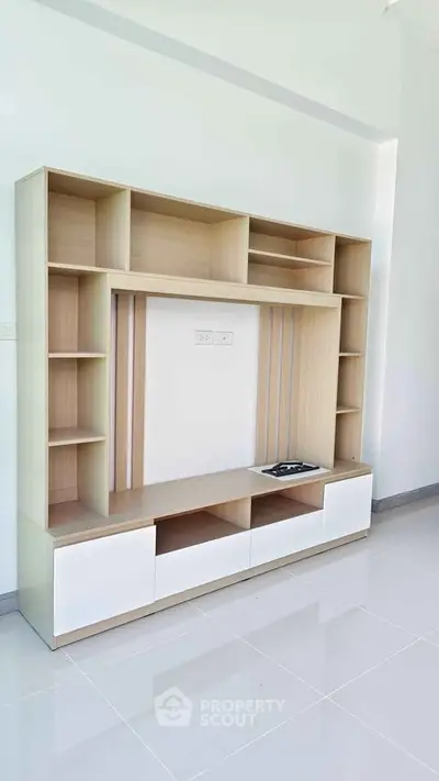 Modern living room with sleek wooden entertainment unit and glossy white flooring.