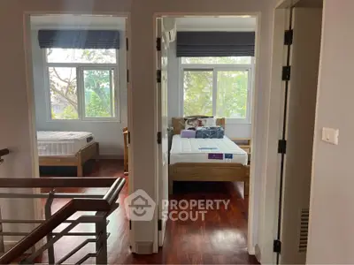 Bright and airy bedroom with wooden floors and large windows in a modern home.
