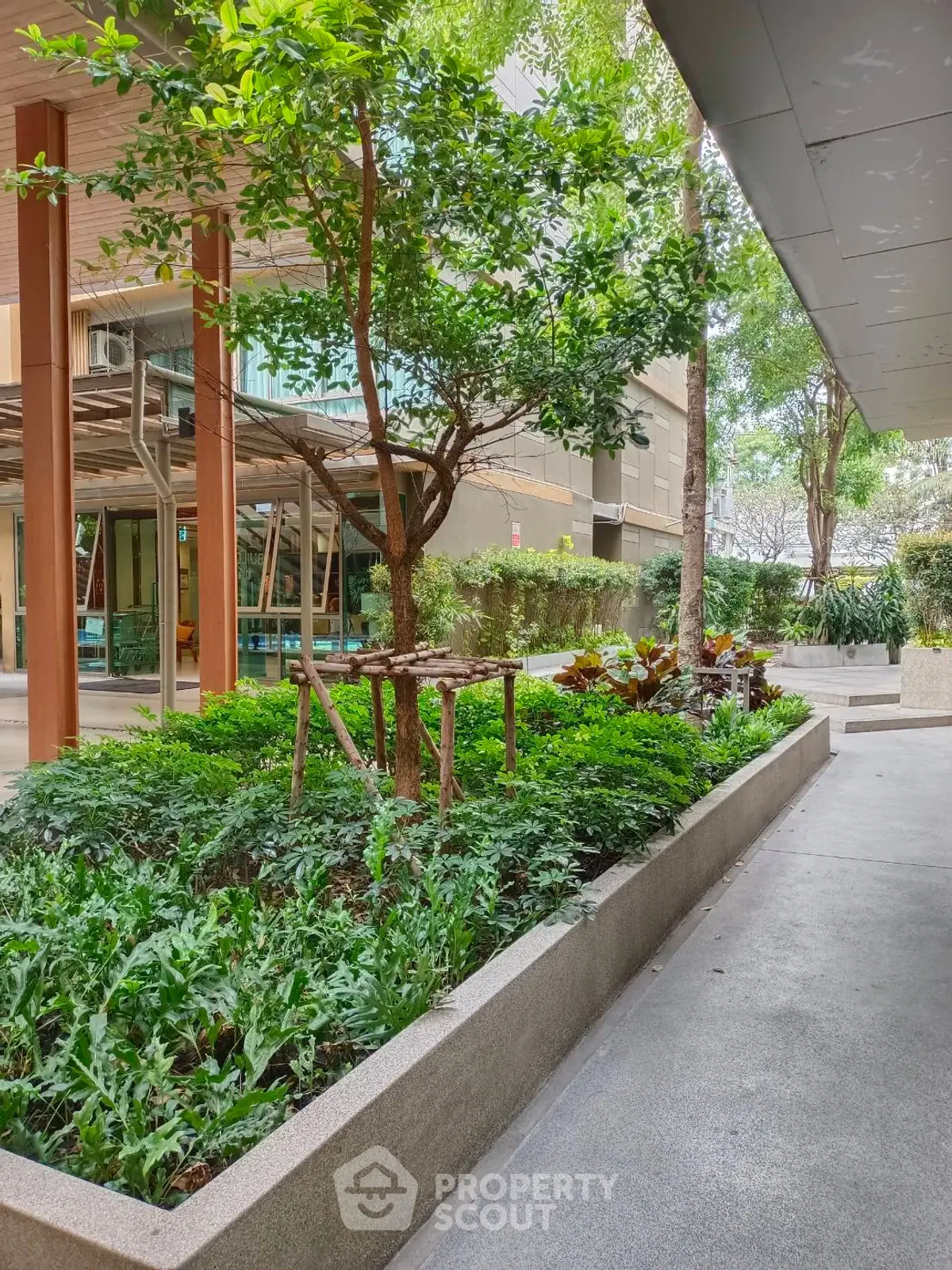 Lush garden area in modern residential complex with greenery and pathways.