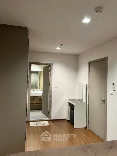 Modern apartment interior with view into bathroom, featuring sleek design and wood flooring.