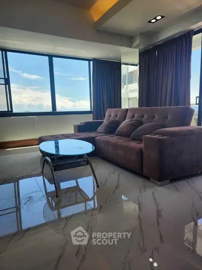 Luxurious living room with panoramic windows and plush sofa, offering stunning views.
