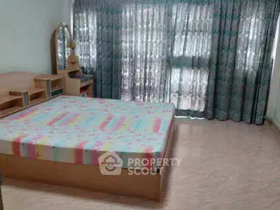 Spacious bedroom with large windows and elegant curtains, featuring a stylish bed and vanity.