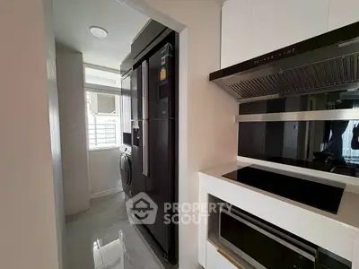 Modern kitchen with sleek appliances and washing machine in compact layout