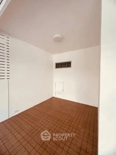 Spacious tiled storage room with ventilation window, ideal for organizing essentials.