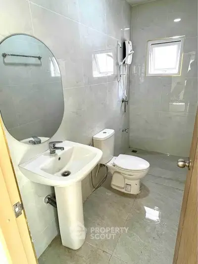 Modern bathroom with sleek fixtures and natural light from small windows.