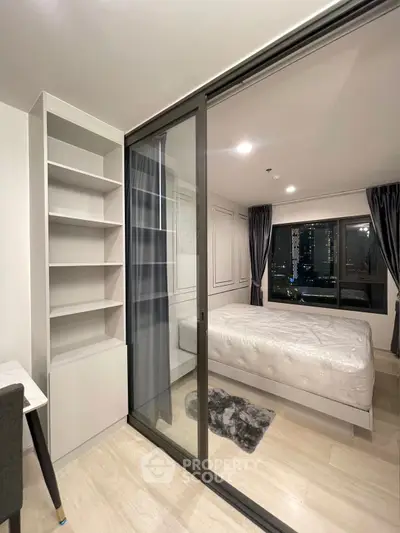 Modern bedroom with city view, featuring sleek sliding glass doors and elegant decor.