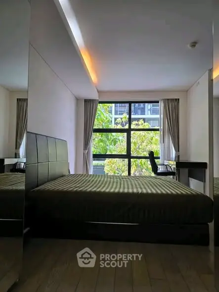 Modern bedroom with large window and stylish decor, offering a serene view of greenery outside.