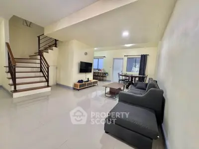 Spacious living room with modern staircase and cozy seating area.