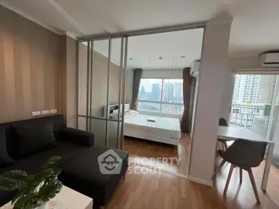 Modern apartment with city view, featuring a cozy living room and bedroom separated by glass doors.