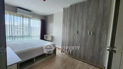 Spacious bedroom with large window and built-in wardrobe in modern apartment