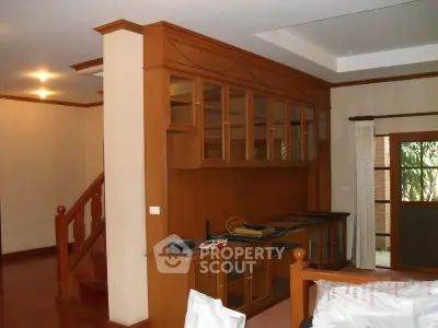 Spacious living room with elegant wooden cabinetry and staircase, perfect for stylish home living.