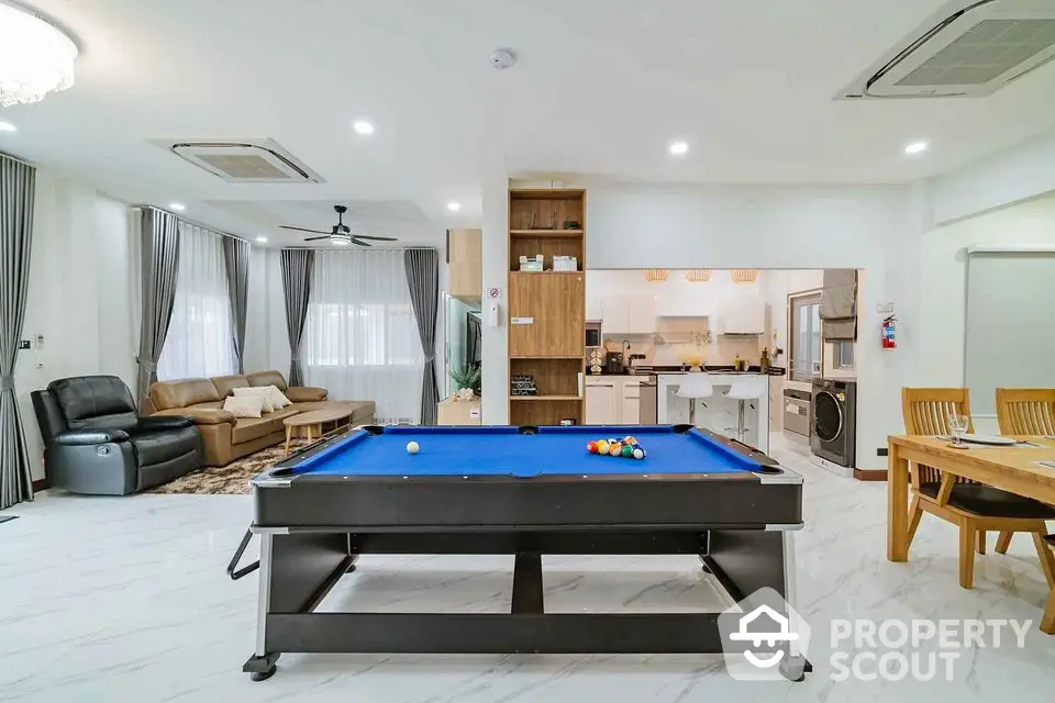 Spacious living room with pool table and modern kitchen in open layout