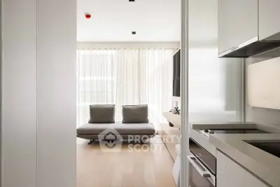 Modern minimalist living room with sleek kitchen, natural light, and cozy seating area.