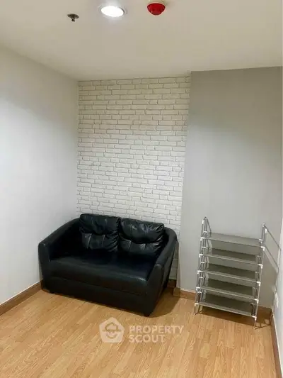 Cozy corner with black leather sofa and modern shelving on wooden floor
