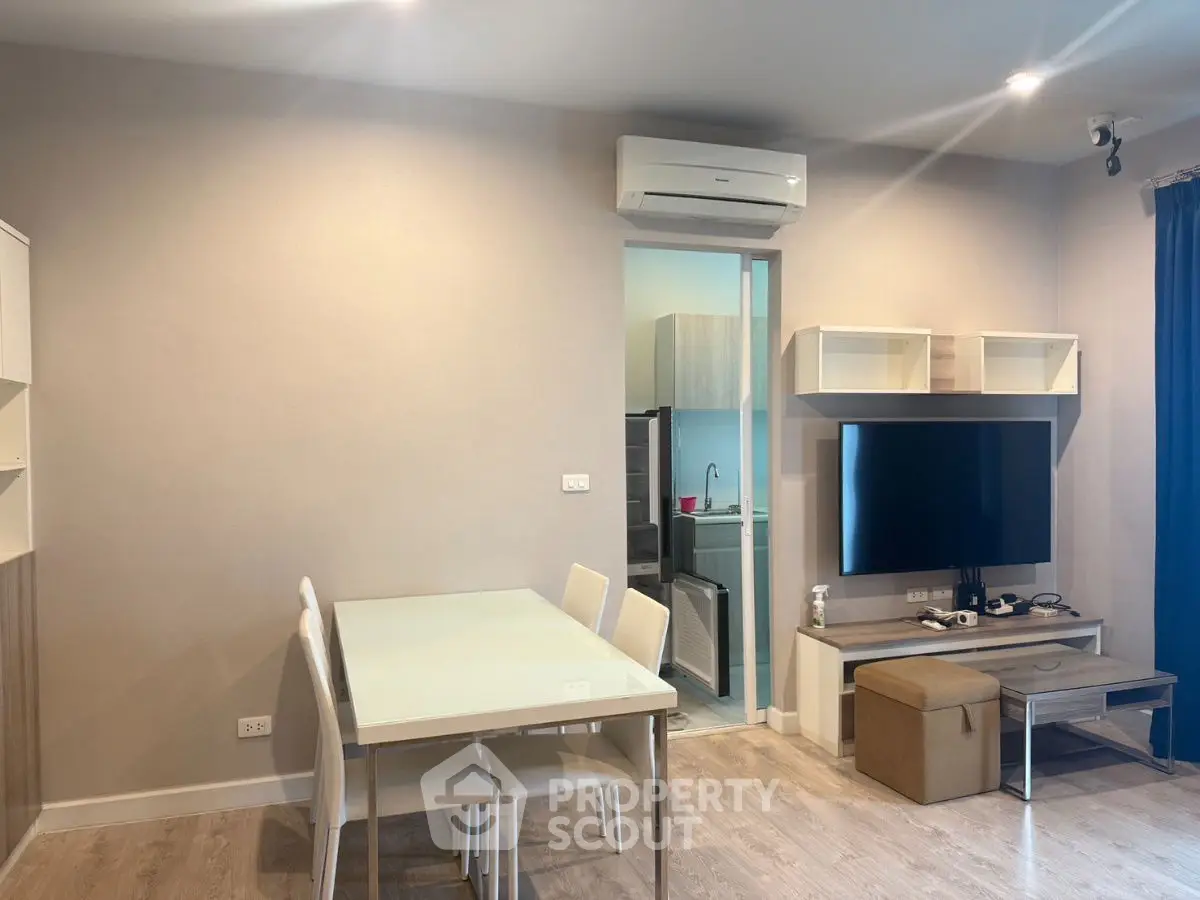 Modern living room with dining area and TV, featuring sleek furniture and neutral tones.