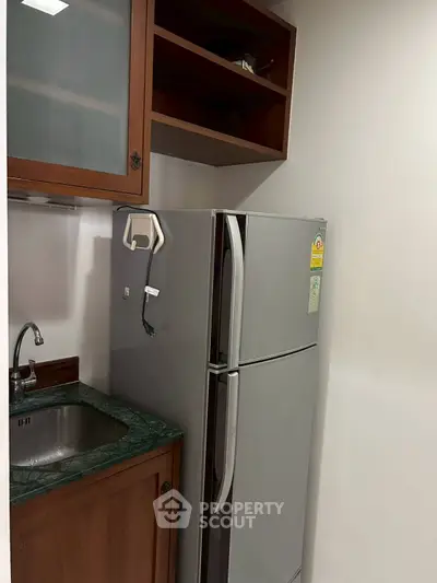 Compact kitchen with fridge and sink, ideal for small apartments or studios.