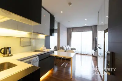 Modern kitchen with sleek black cabinets and integrated appliances flows into a cozy living area with ample natural light, perfect for urban living.