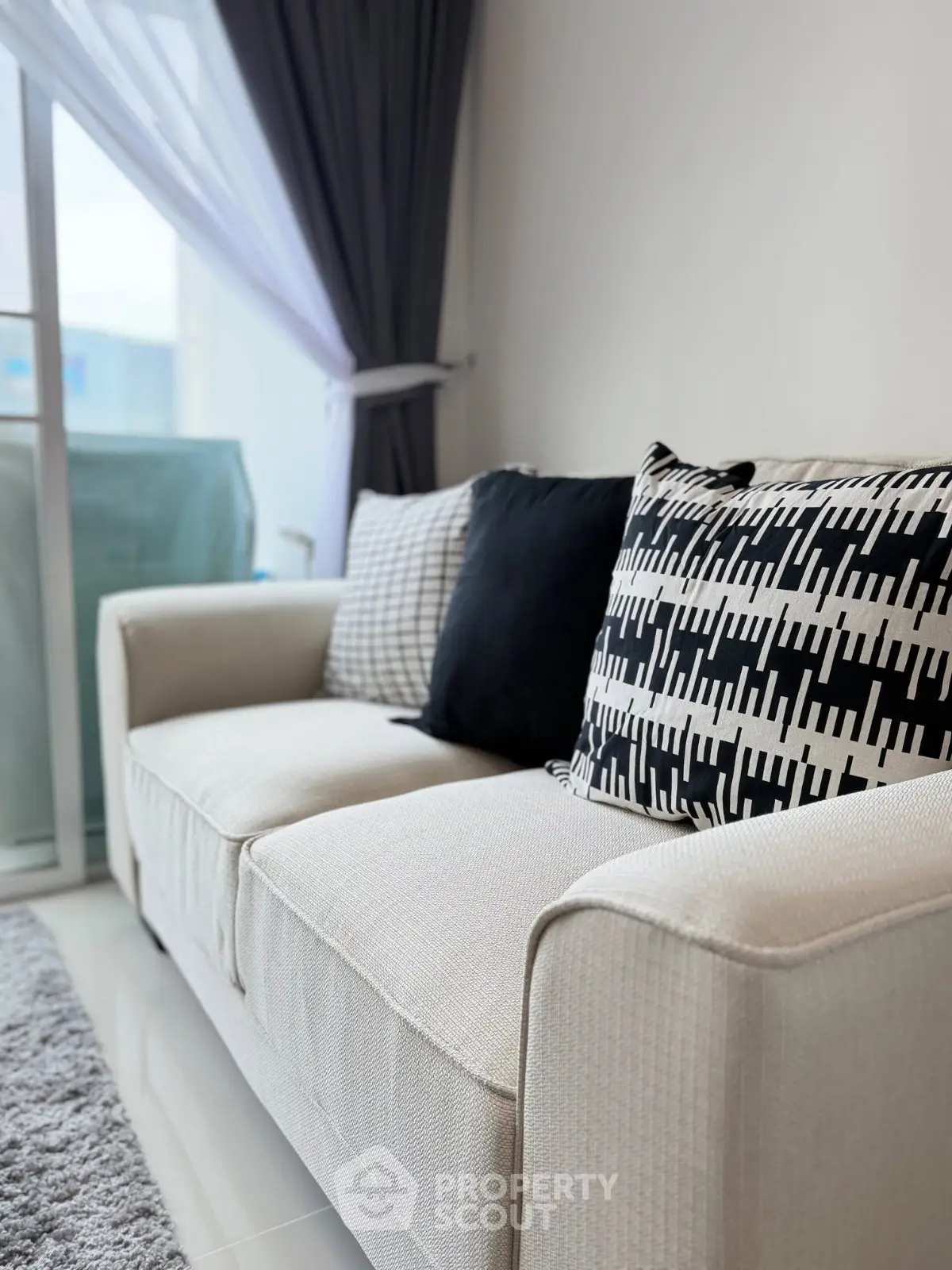 Modern living room with stylish sofa and decorative pillows, featuring a bright window view.