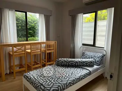 Cozy bedroom with single bed and window-side dining area, perfect for compact living.